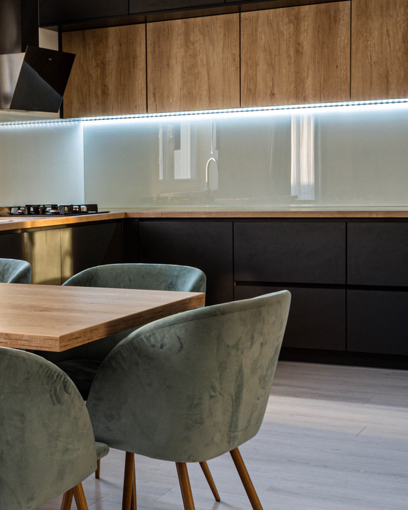 modern kitchen with glass splashback and black and wood cabinet doors