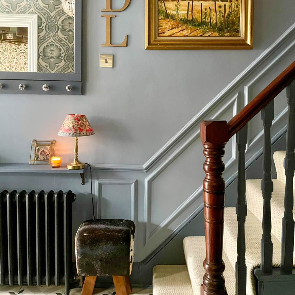 Staircase showing traditional mouldings painted blue-grey with decorative home accessories.