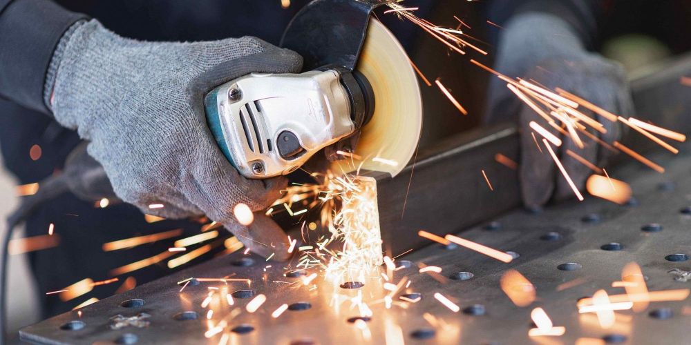 person cutting steel box section with angle grinder