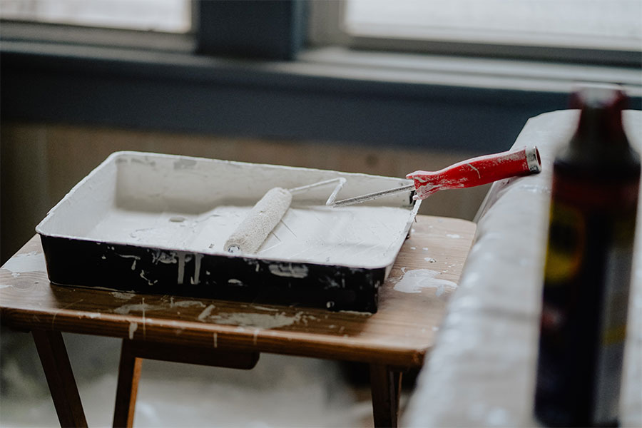 Paint roller and tray filled with white paint