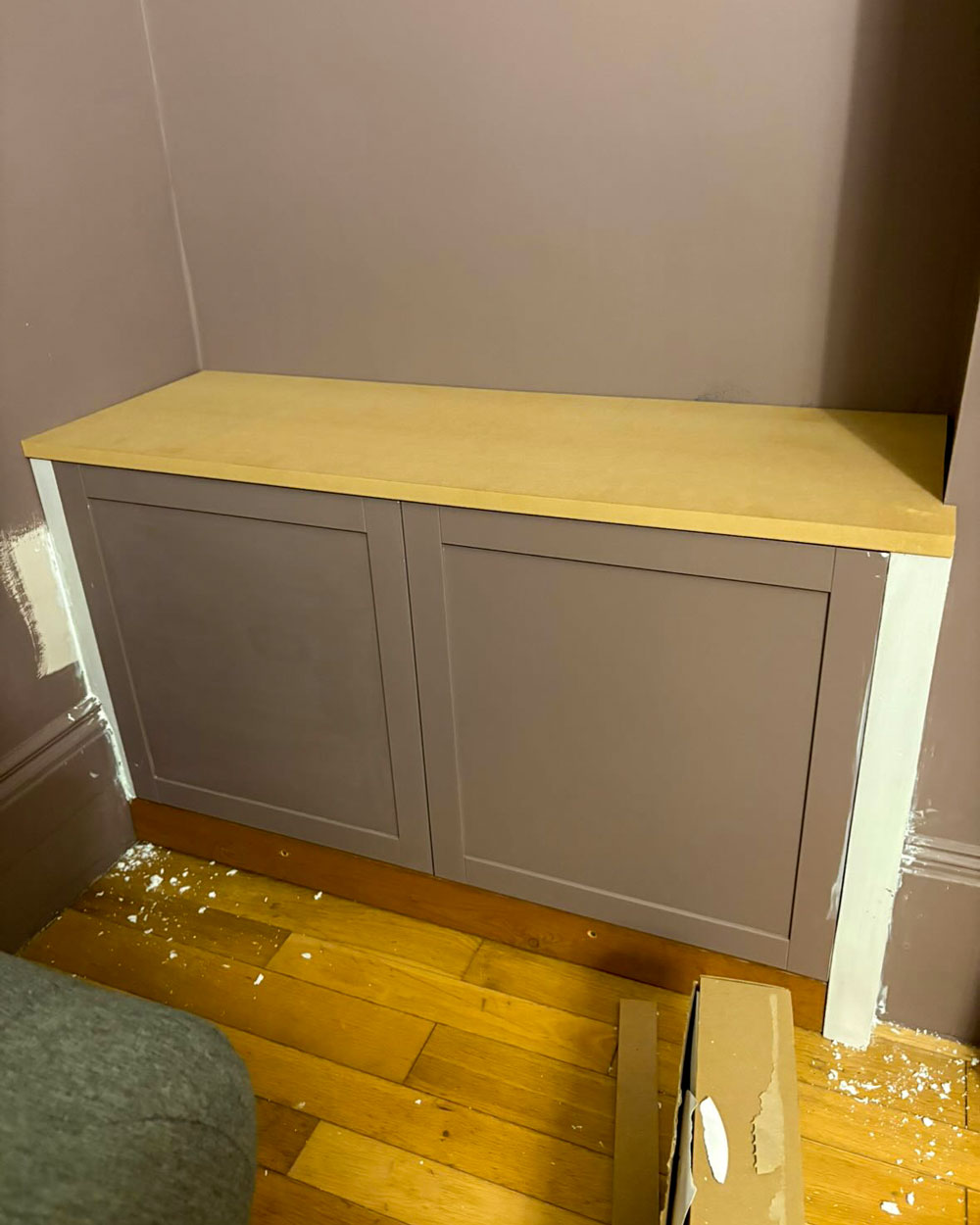 Unpainted MDF top panel fitted to IKEA Besta cabinets during built-in transformation, with filler applied to side gaps.